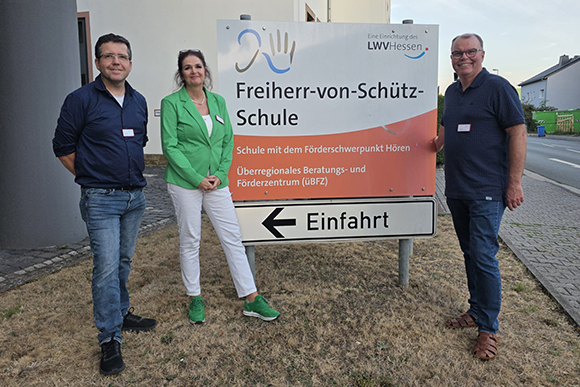 Zwei Männer udn eine Frau stehen neben dem Einfahrts-Schild der Freiherr-von-Schütz-Schule